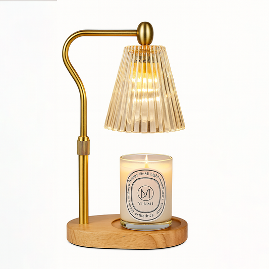 Gold candle warmer lamp with a ribbed glass shade and a lit scented candle on a wooden base, displayed on a white background.